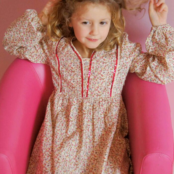 Pour la rentrée scolaire comme pour tous les jours, on craque pour cette magnifique robe imprimée fleuri liberty rose et beige à paillettes rose fuchsia. La robe à manches longues bouffantes est inspirée des robes du moyen âge avec plastron bordé de strass rose et lien sur le côté pour resserrer la robe sur les côtés. Modèle exclusif de la marque de mode Française chic pour enfant produite en commerce équitable et quantité raisonnée c'est la faute à Voltaire/ La Faute à Voltaire.