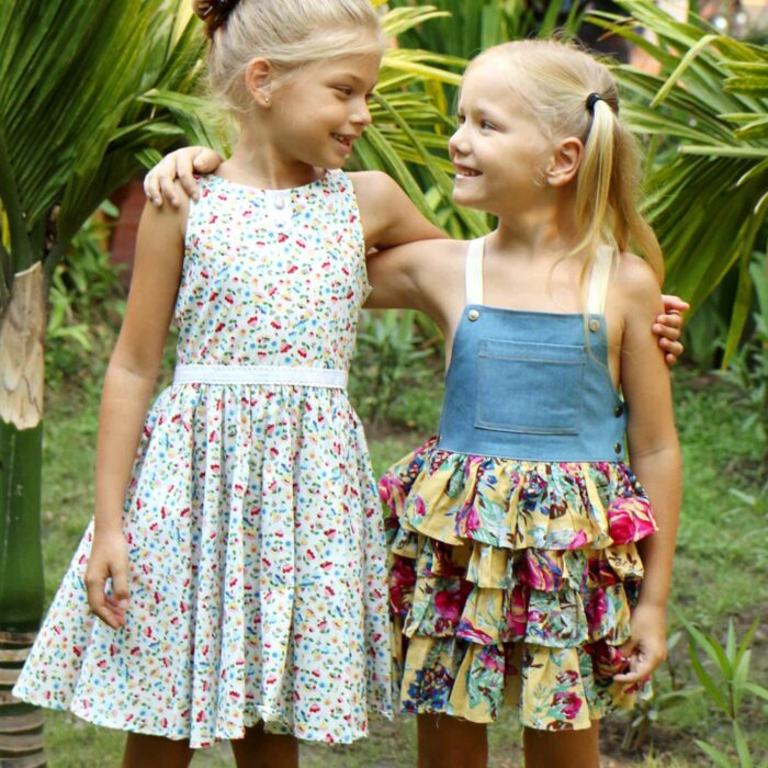 Robe salopette été fille avec haut en coton jean denim bleu et bas de la robe à volants fleurie jaune et multicolor, bretelles croisées dans le dos ajustables. Modèle robe salopette à volants pour filles, fillettes de la marque de mode enfant LA FAUTE A VOLTAIRE