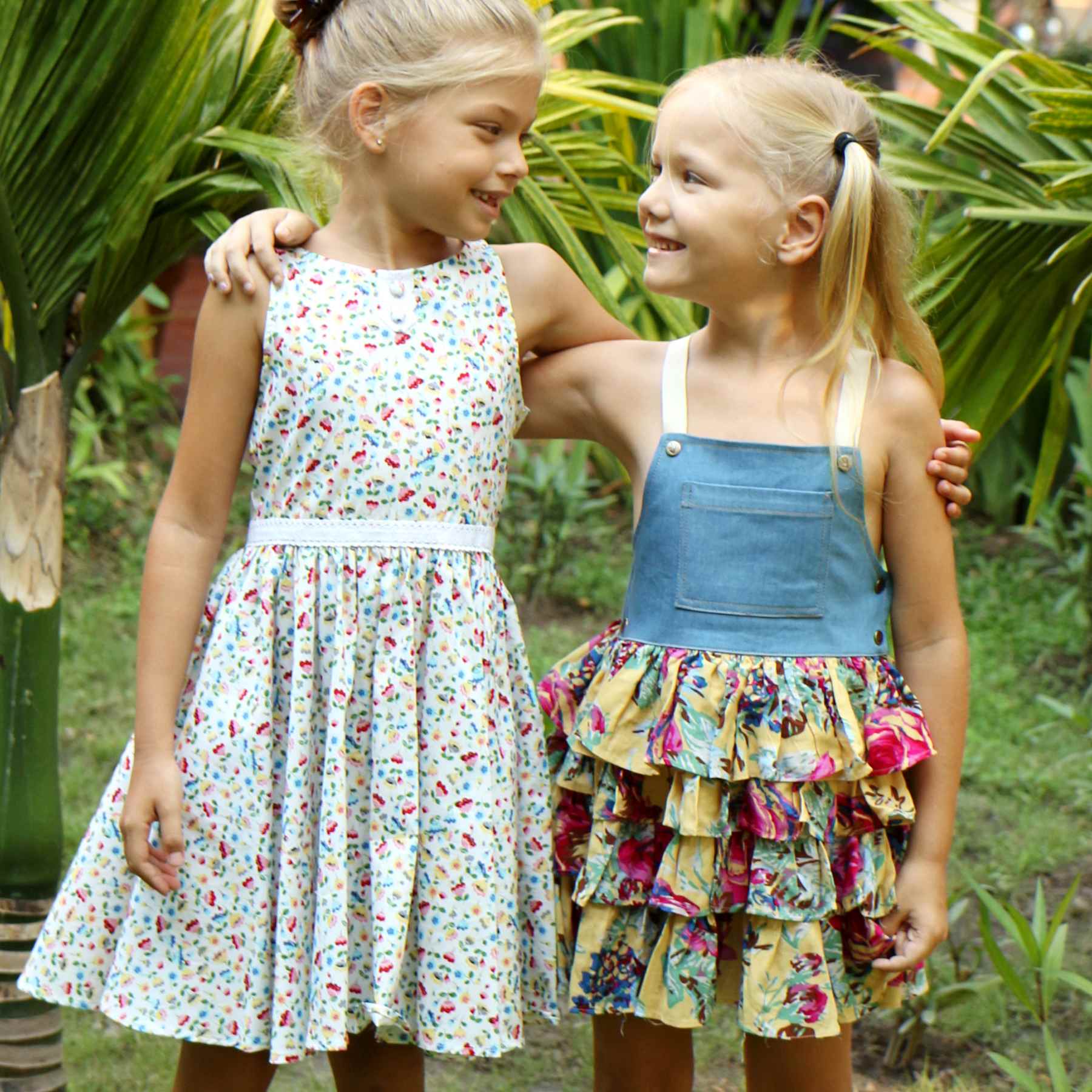 Robe salopette été fille avec haut en coton jean denim bleu et bas de la robe à volants fleurie jaune et multicolor, bretelles croisées dans le dos ajustables. Modèle robe salopette à volants pour filles, fillettes de la marque de mode enfant LA FAUTE A VOLTAIRE