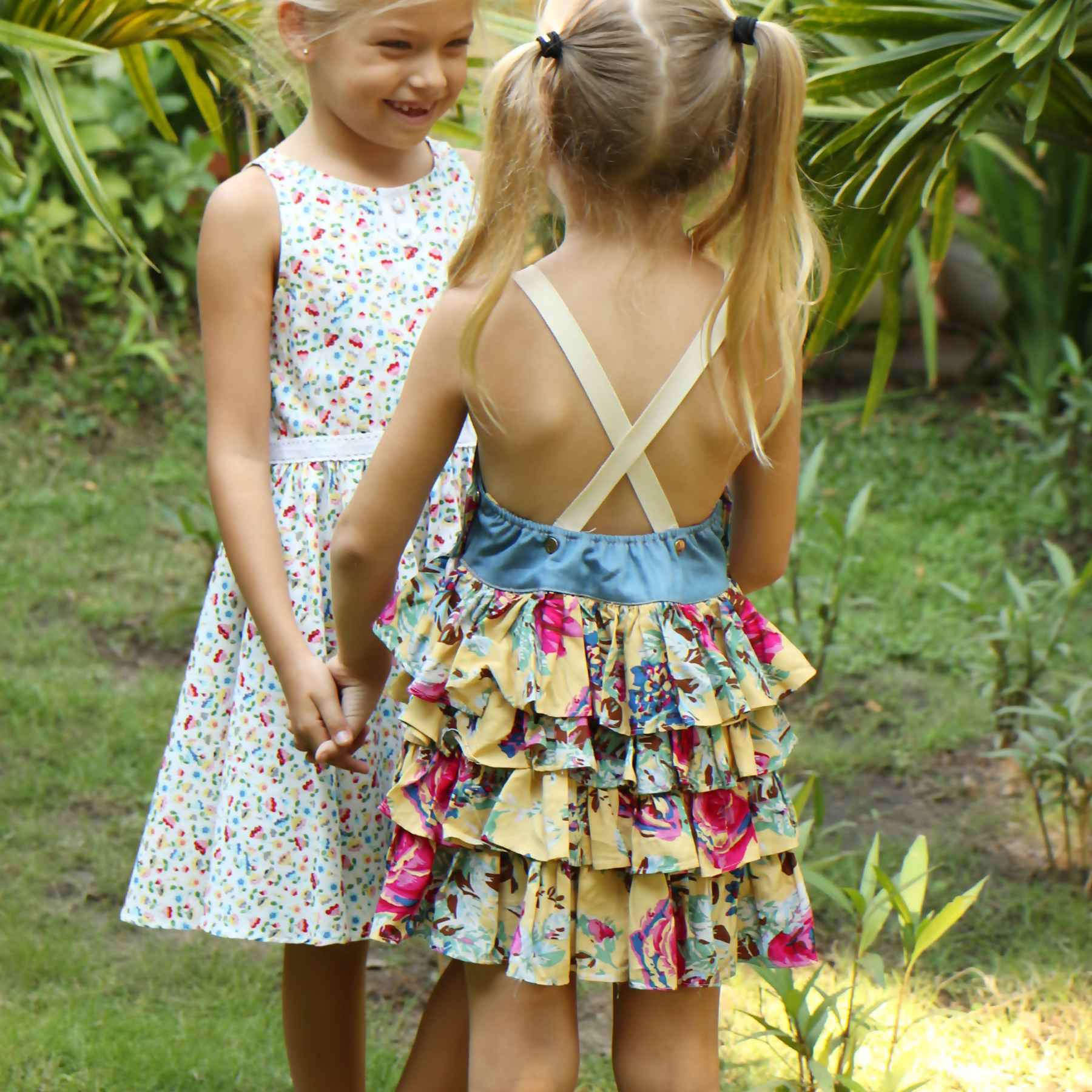Robe salopette été fille avec haut en coton jean denim bleu et bas de la robe à volants fleurie jaune et multicolor, bretelles croisées dans le dos ajustables. Modèle robe salopette à volants pour filles, fillettes de la marque de mode enfant LA FAUTE A VOLTAIRE