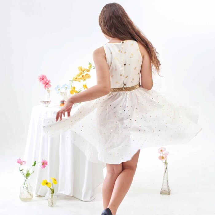 Vous Recherchez une Robe Blanche et Or pour un Mariage ? Une Soirée ? Un Anniversaire à Célébrer en Été ou une Robe de Nouvel An pour la Fin d'Année ? Craquez pour cette Robe de Soiré et Fête Polyvalente que toutes les Filles, Fillettes et Ados de 2 à 16 ans pourront Porter et faire Virevolter à l'Infini. Coupée en Demi-Lune et Froncée à la taille, cette Robe Patineuse Tourne à l'Horizontal pour le plus grand Bonheur de votre Princesse. Coupée en 3 Matières : Lin Blanc Imprimé Petits Palmier Dorés sur le Buste, Tulle Blanche à Paillettes Dorées sur la Jupe Doublée de Coton blanc. Emmanchures à l'Américaine Bordés d'un Biais Doré pour Dessiner de Jolies Épaules. Taille Soulignée par une ceinture Fixe en Paillettes Dorée. Cette Robe Forme Trapèze est de la Collection Tenue de Mariage et Fêtes de la Marque de Mode Française pour Enfants C'est la faute à Voltaire.