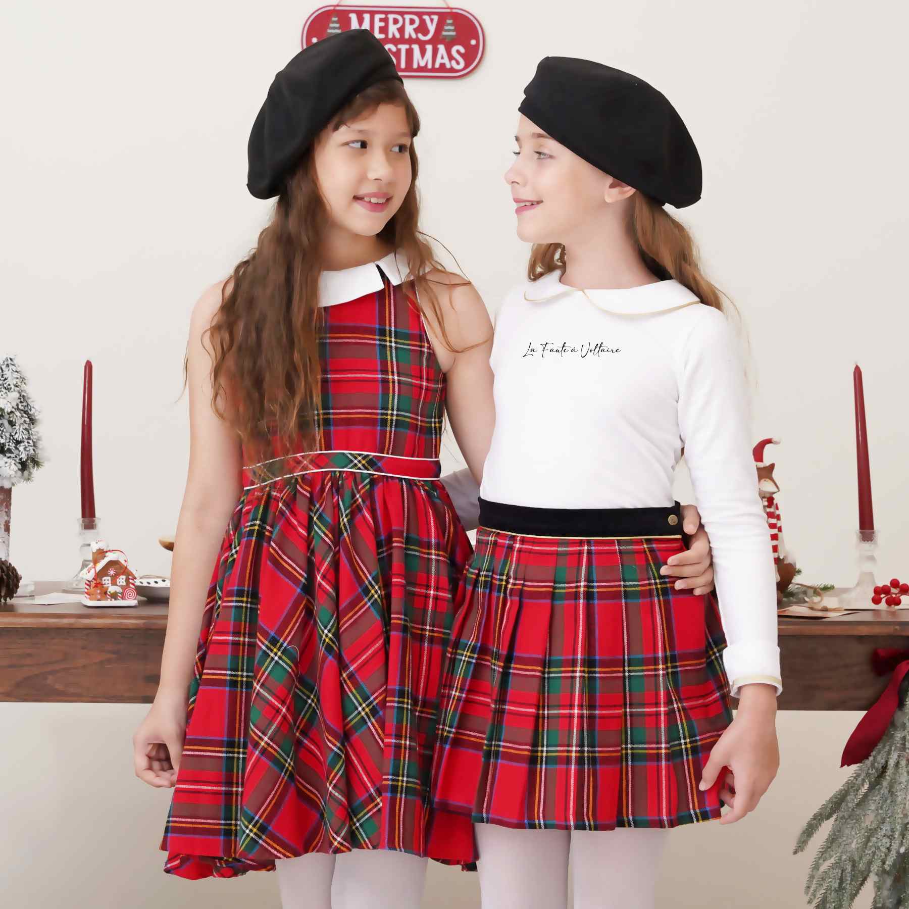 Une Élégante Robe Patineuse qui Tourne en Flanelle Carreaux Tartan Rouge et Vert, sans Manche, Col Claudine Blanc Tourné sur le Côté, Taille Marquée par Deux Biais de Coton Blanc, Emmanchures Américaines. Pour les Fêtes de Noël et Tous les Jours de l'Automne et Hiver. A porter avec des Collants Fins Blanc et un Gilet Blanc. Marque de Mode Rétro-Chic et Commerce Équitable de la Marque de Mode pour Enfant La Faute à Voltaire.