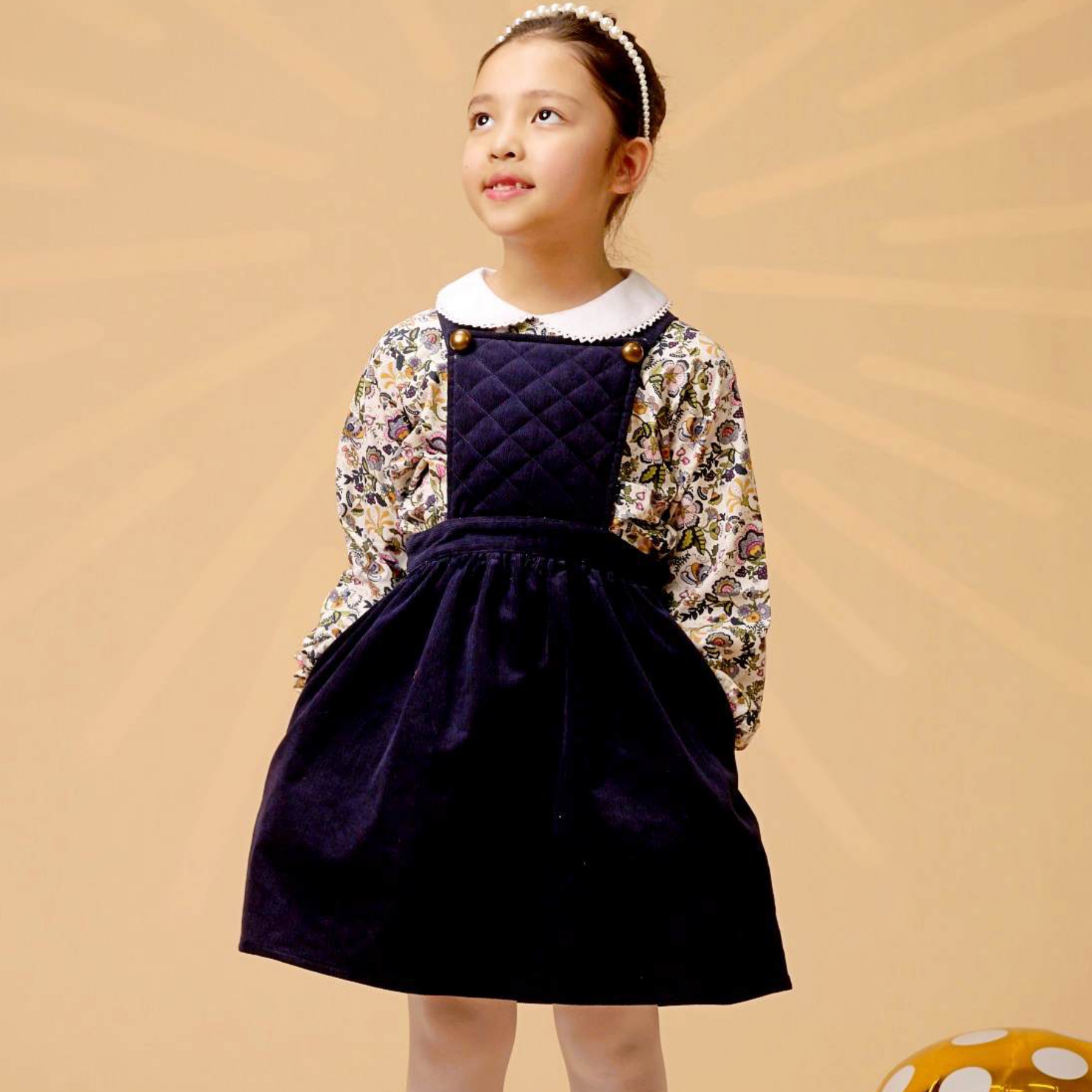 Offrez Lui cette Magnifique Robe Salopette Hiver Fille en Velours Bleu Marine, à Bretelles Larges Croisées dans le Dos. Fermeture Couleur Bronze. Avec Poches Invisibles sur les Côtés. Taille Élastique dans le Dos. Robe Rétro Chic de la Marque de Mode Française pour enfants La Faute à Voltaire.