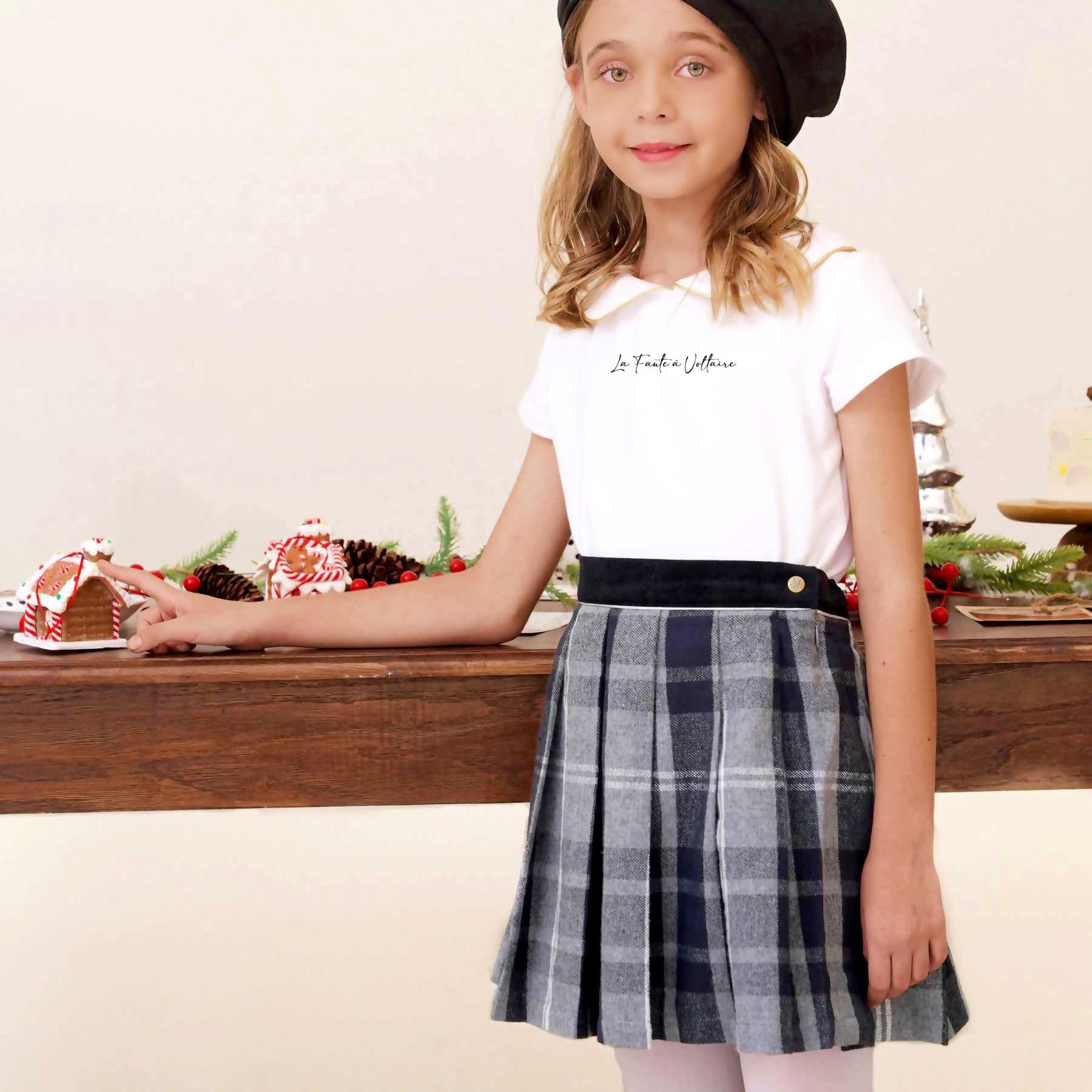Offrez une Magnifique Tenue Classique Chic Tendance "Preppy". Composée d'un Ensemble de 2 pièces de Mode avec la Jupe Plissée en Laine Tartan Gris London et le T-Shirt Blanc "Sophia" à Manches Courtes et Col Claudine souligné d'un Biais Doré et Slogan La Faute à Voltaire sur la poitrine. Pour un look Écolière, un look "Collège" ou le Style K-pop pour les Ados, cette Tenue Convient à toutes les jeunes Fashionistas entre 2 et 16 Ans de la Marque de Mode Française pour Enfants La Faute à Voltaire.