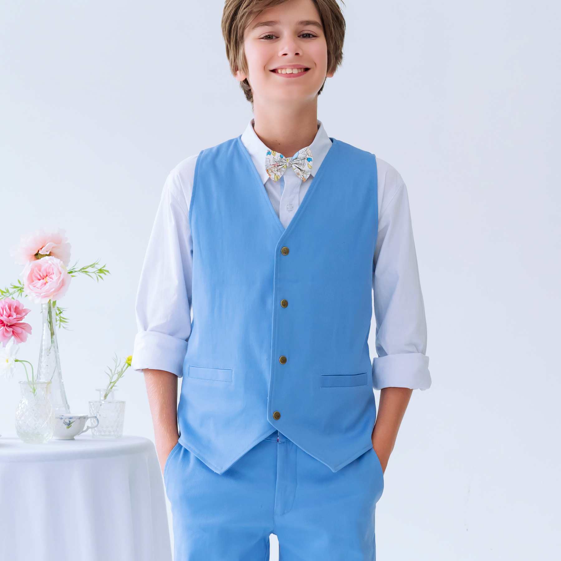Photo portée du gilet de costume bleu ciel pour garçon de 2 à 16 ans assorti au pantalon Ambroise et bermuda Jimini bleu ciel de la même collection Cérémonie été pour enfant.