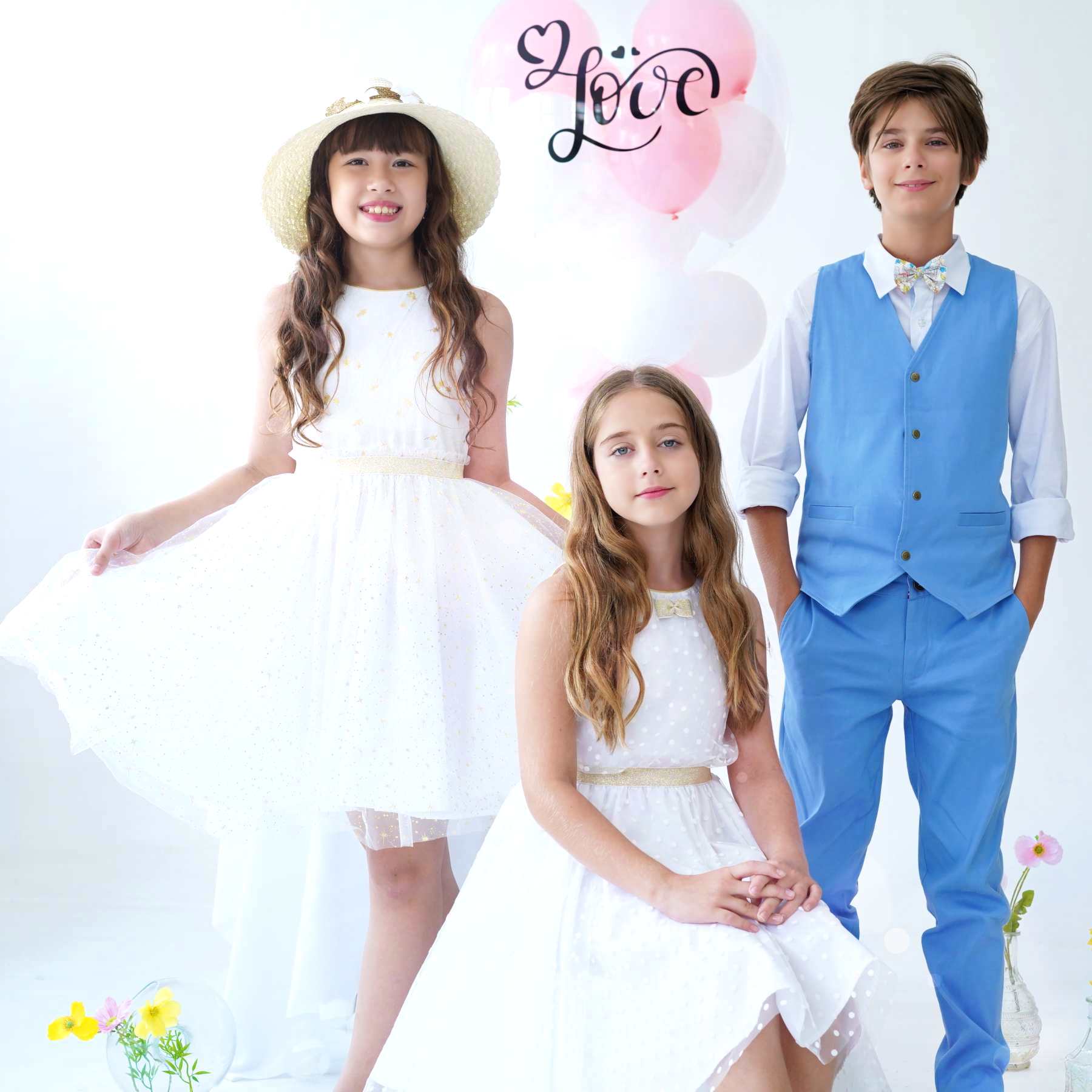 Photo portée tenues de cérémonie enfant avec le pantalon chino bleu ciel Ambroise, gilet de costume assorti et robes blanches et dorées en tulle pour filles