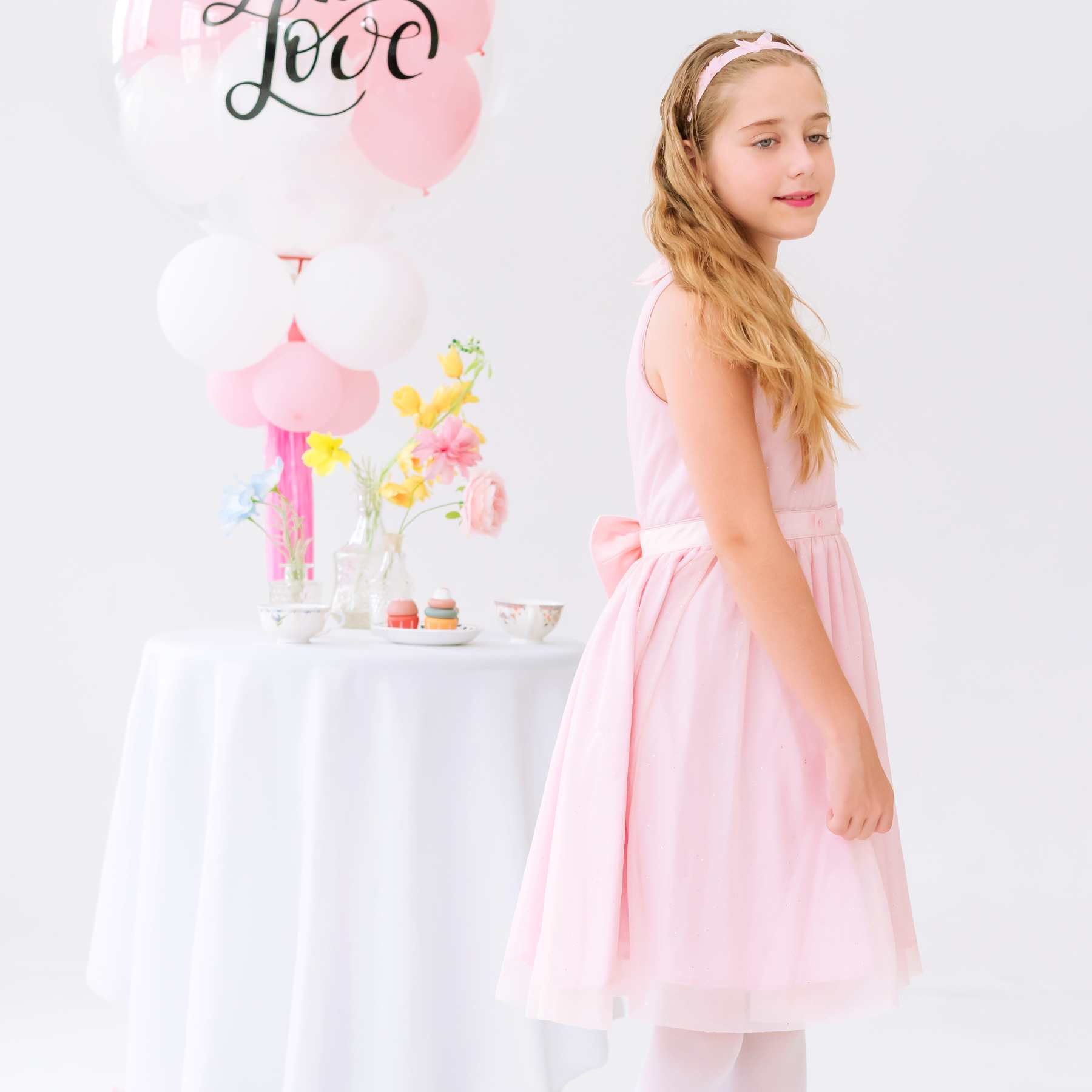 Robe de mariage fille rose poudrée Hepburn portée, coupe patineuse, ceinture ornée de papillons et grand nœud au dos, tenue de mariage chic de la marque de mode pour enfants La Faute à Voltaire