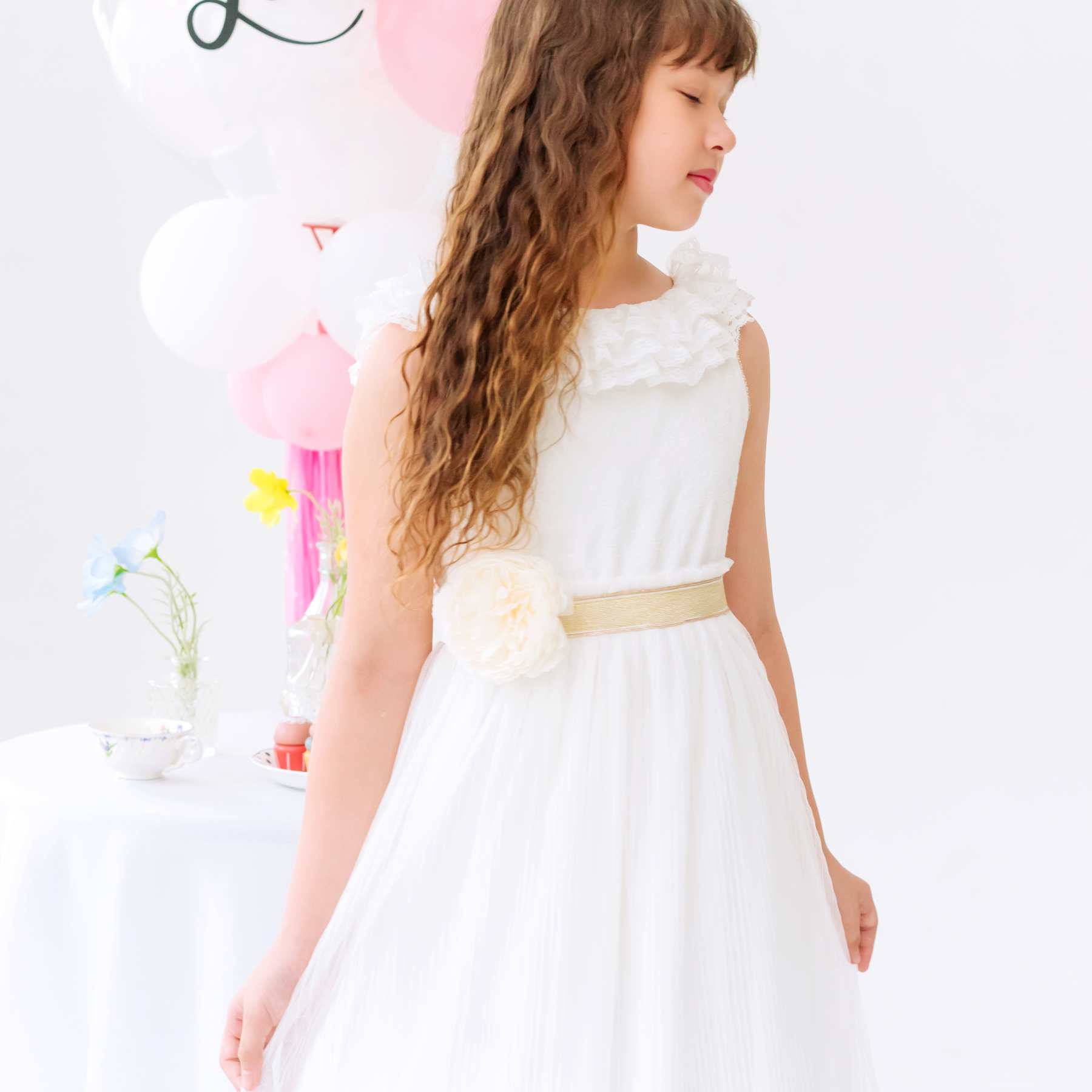 Robe demoiselle d’honneur fille blanche longue Éléonore portée par une enfant, en voile plissée avec dentelle fine au col, dos en V, ceinture dorée, tenue de mariage et cérémonie enfant de la marque Française La Faute à Voltaire