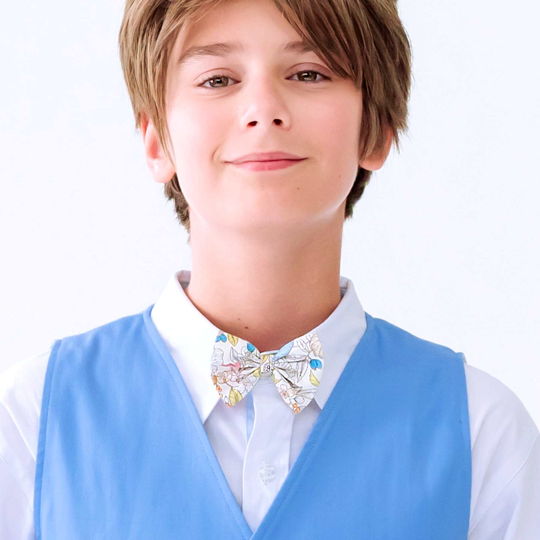 Photo portée du noeud papillon liberty garçon fleuri jaune clair. Idéal pour les mariages et cérémonies estivales, ce noeud papillon liberty jaune clair est identique à celui des robes de cérémonies liberty jaune clair fille afin d'harmoniser les robes de demoiselles d'honneur et costume des garçons d'honneur. Disponible du 2 au 16 ans.